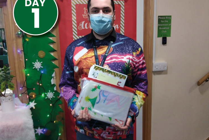 A man in a festive jumper holding pictures that will be donated to KMPT A man in a festive jumper holding pictures that will be donated to KMPT