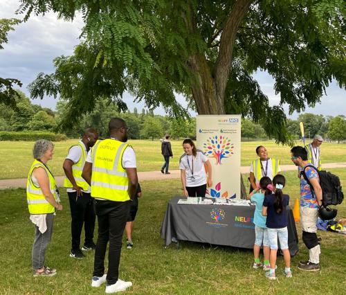 staff members, volunteers and children at a trust stall outside.